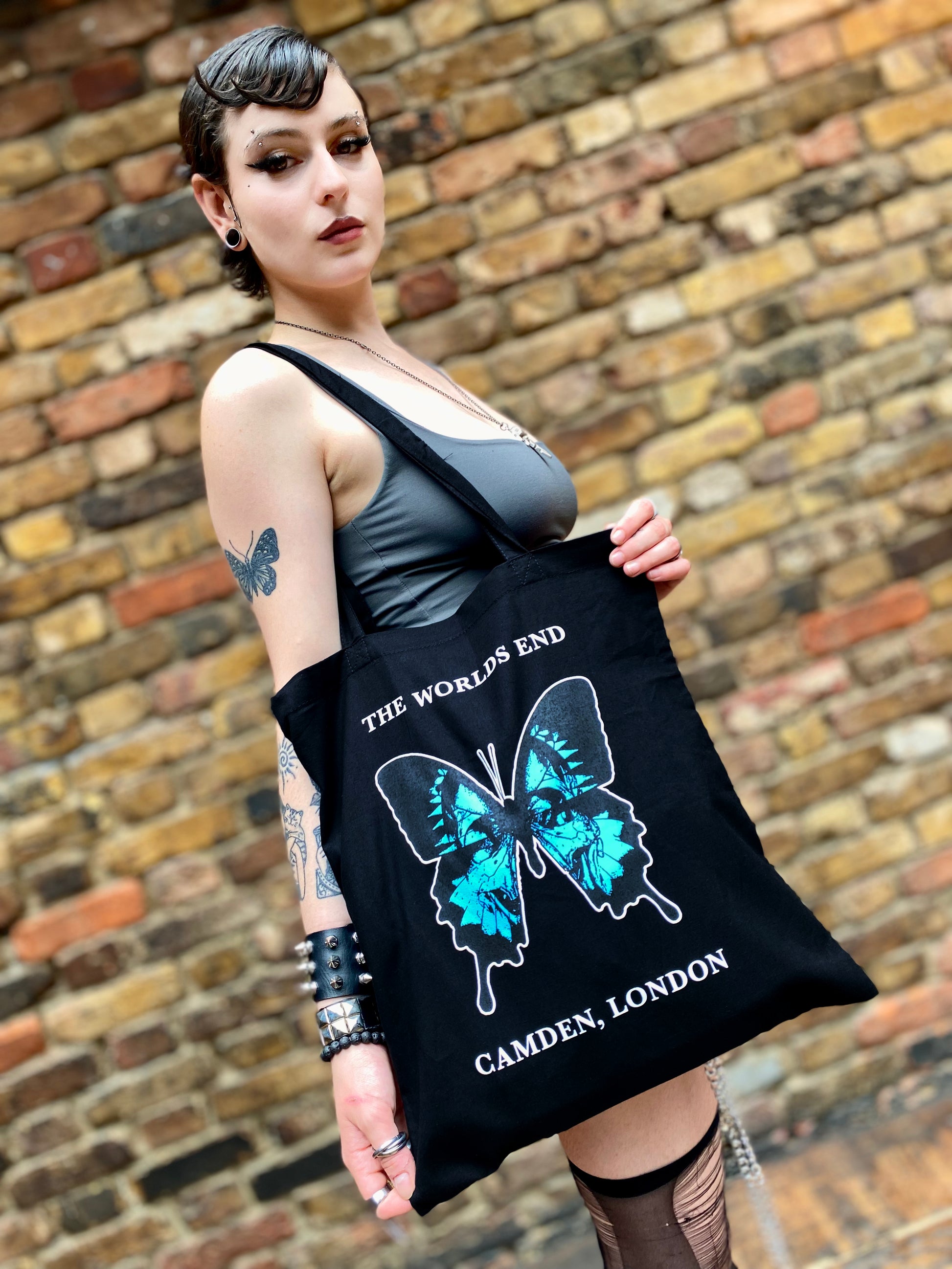 Person holding a black tote bag with butterfly design and text.