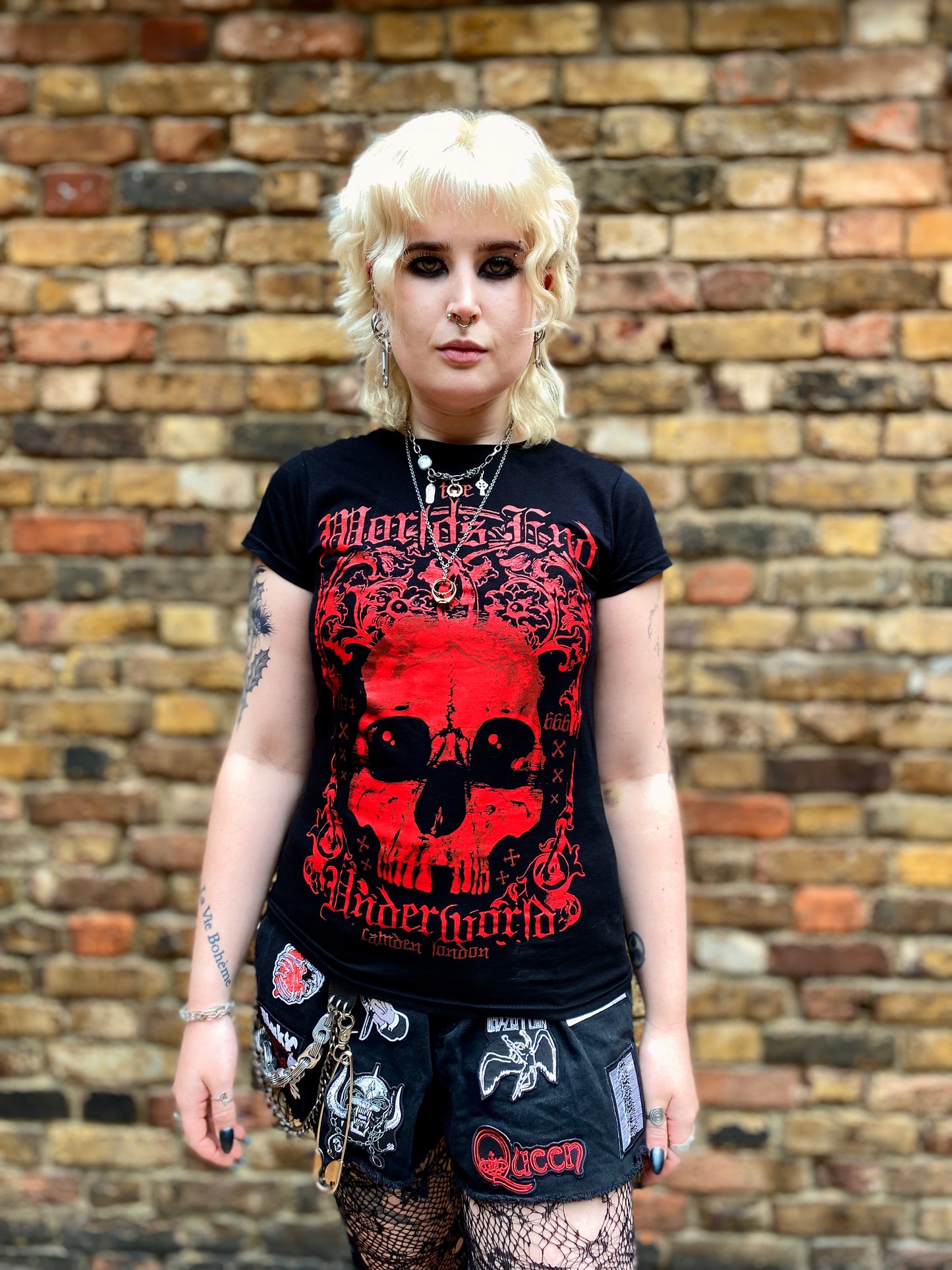 Person wearing a black t-shirt with red graphic design in front of a brick wall
