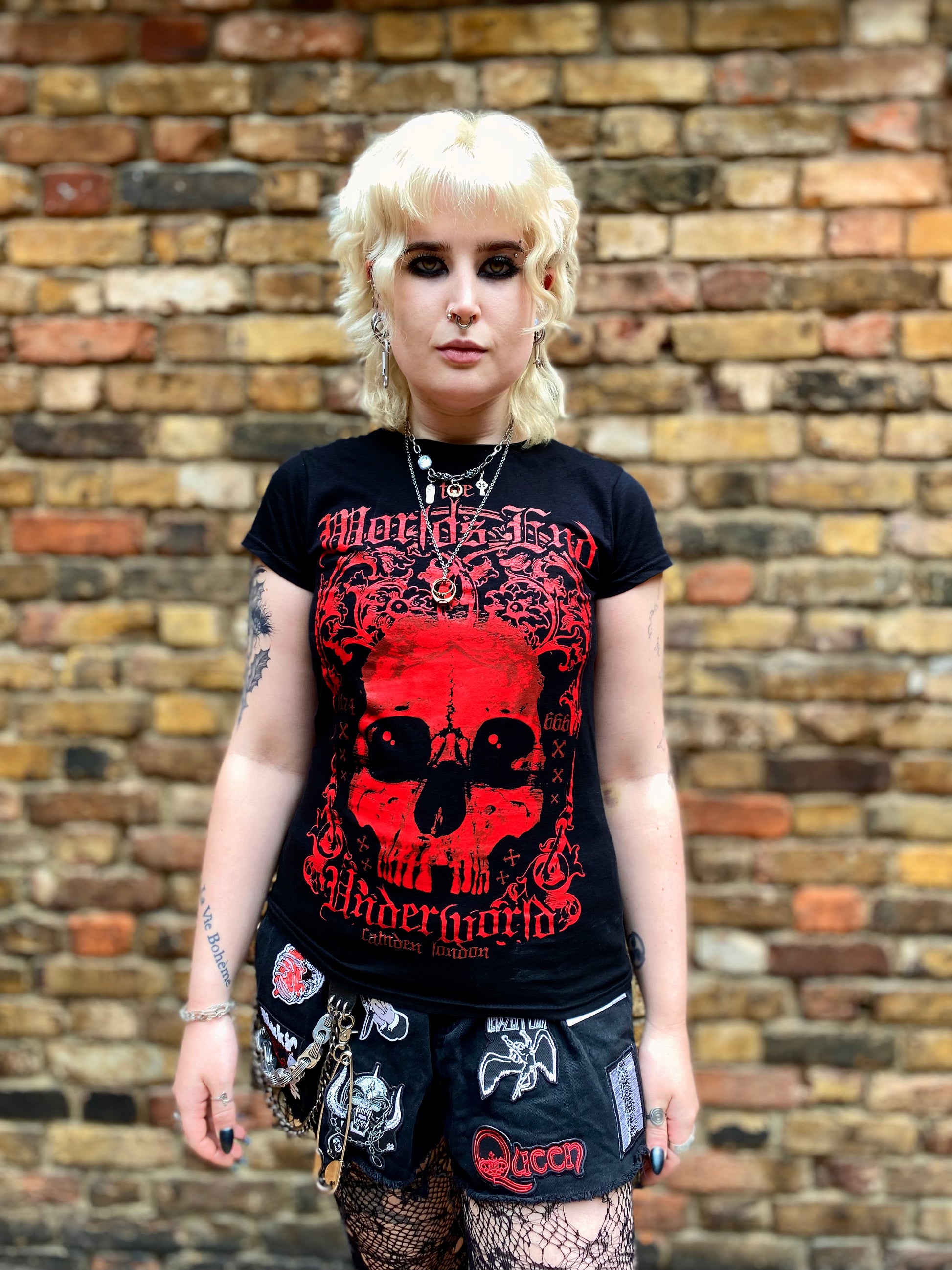 Person wearing a black t-shirt with red graphic design in front of a brick wall